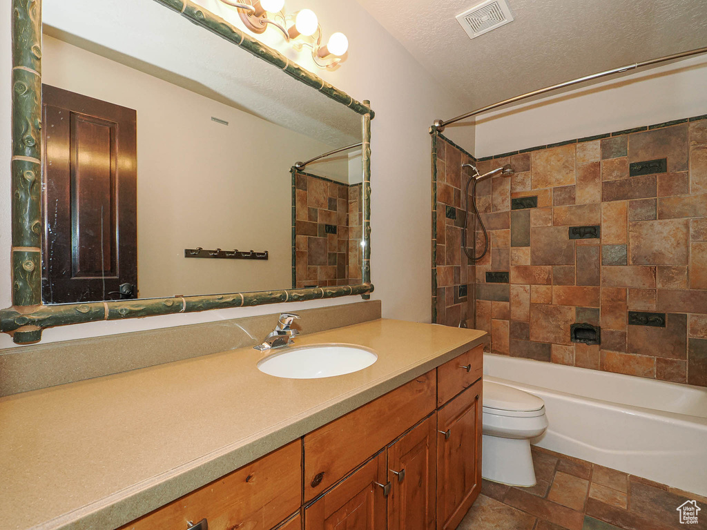 Full bathroom with a textured ceiling, toilet, shower / bath combination, vanity, and visible vents