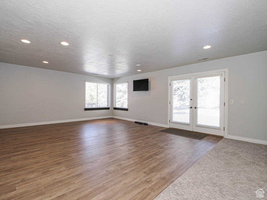 Empty room featuring visible vents, baseboards, wood finished floors, a textured ceiling, and french doors