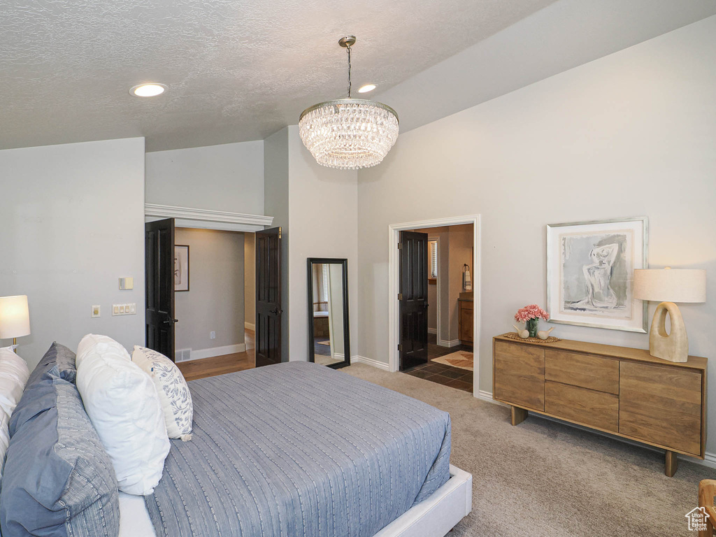Bedroom with carpet floors, lofted ceiling, a textured ceiling, a chandelier, and baseboards
