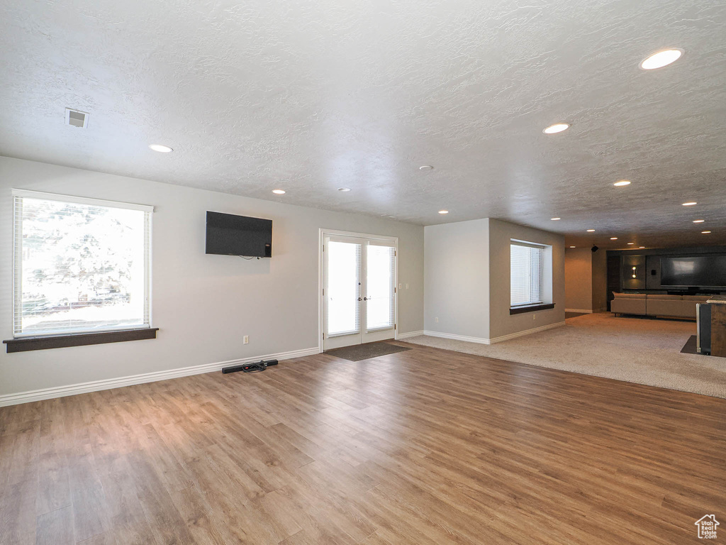 Unfurnished living room featuring a textured ceiling, recessed lighting, baseboards, and light wood-style floors