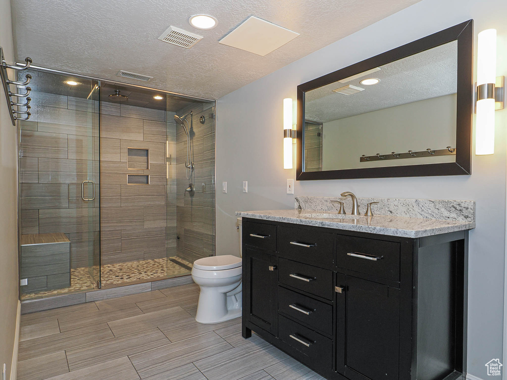 Bathroom featuring visible vents, vanity, toilet, and a textured ceiling