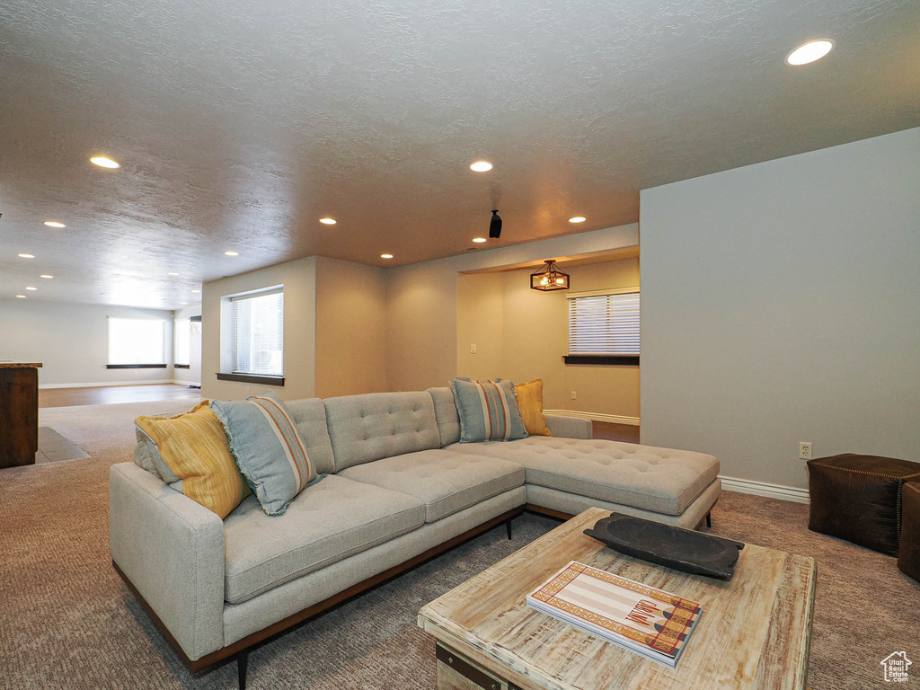 Carpeted living area featuring a textured ceiling, recessed lighting, and baseboards