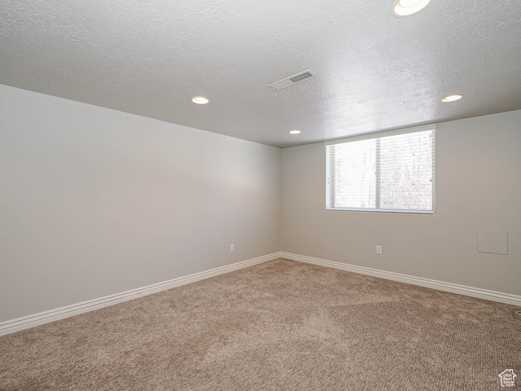 Carpeted empty room with baseboards, visible vents, a textured ceiling, and recessed lighting