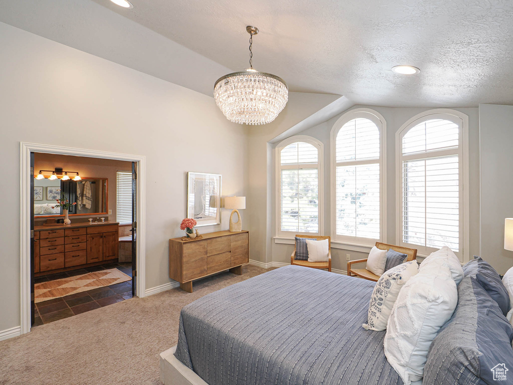 Bedroom featuring baseboards, ensuite bath, vaulted ceiling, a textured ceiling, and dark carpet