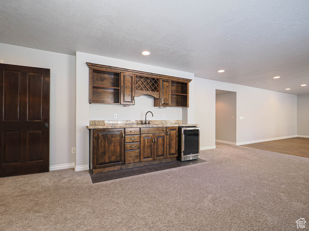 Bar with beverage cooler, dark carpet, a sink, and indoor wet bar