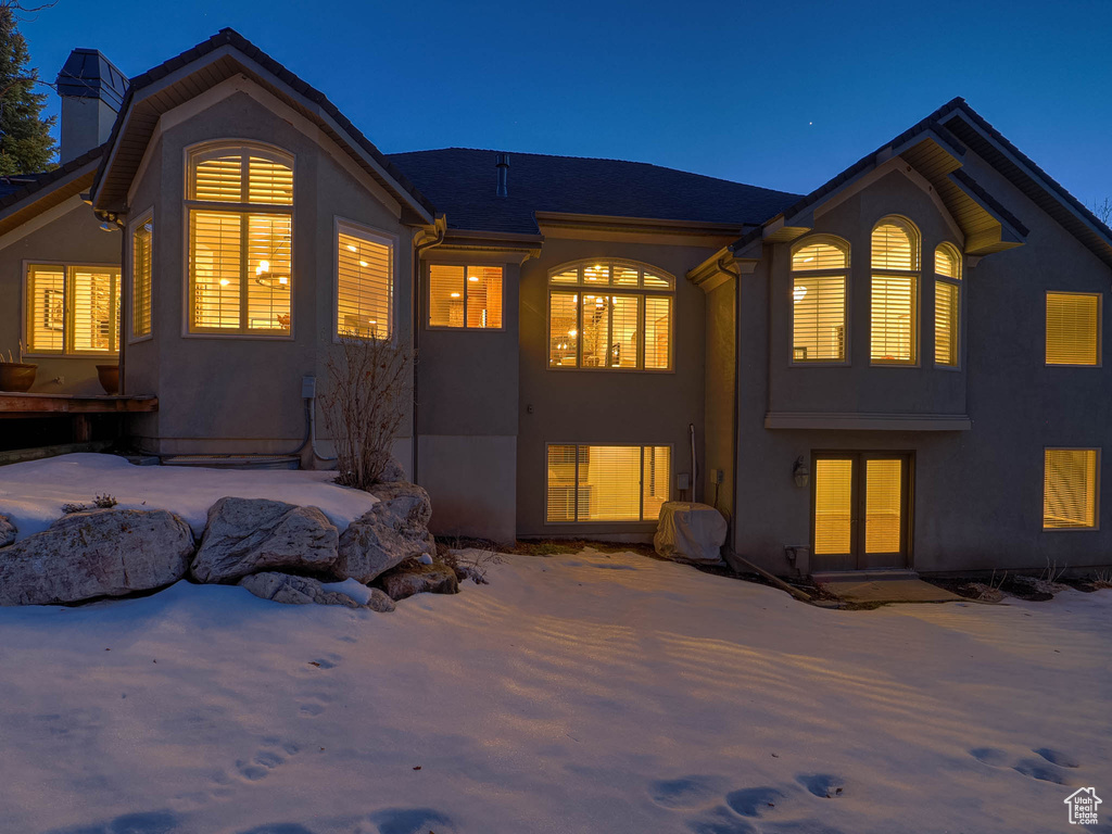 Snow covered back of property featuring a chimney and stucco siding