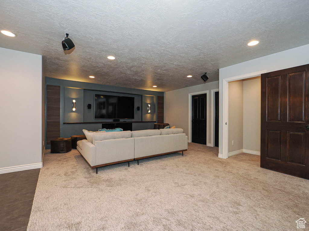 Living room featuring baseboards, a textured ceiling, light carpet, and recessed lighting