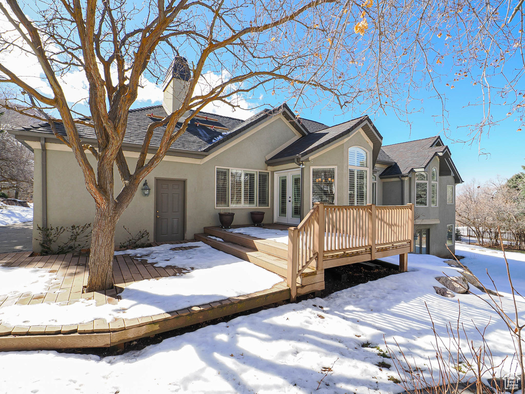 View of front of home with a chimney, french doors, a deck, and stucco siding