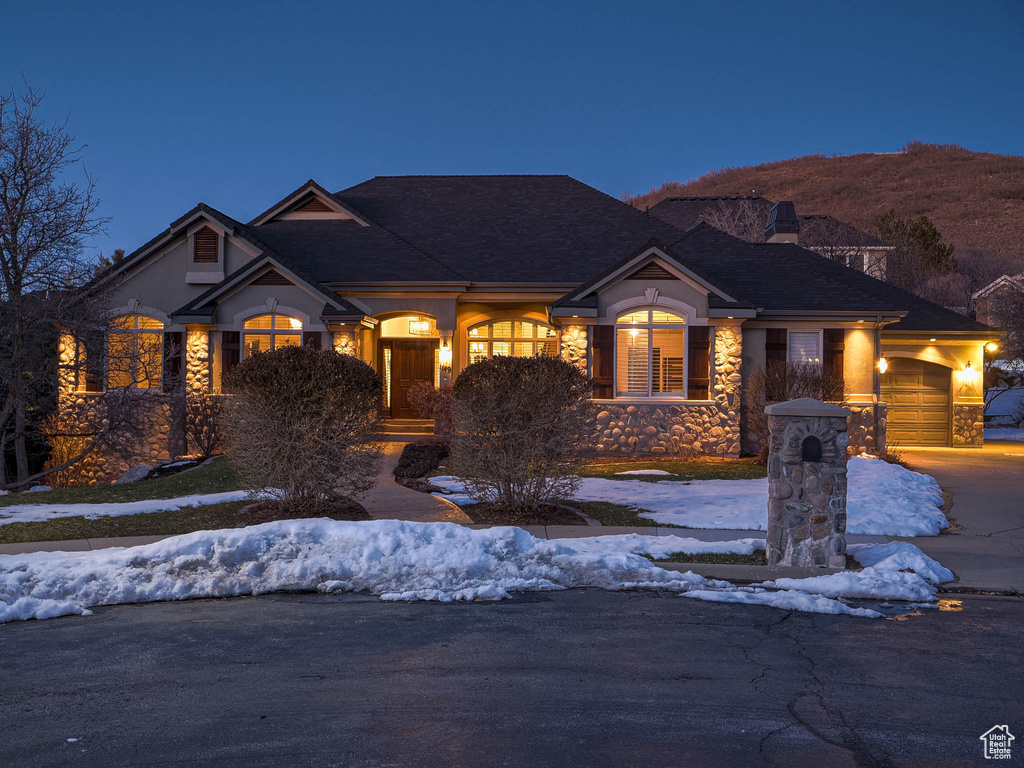 View of front of property with an attached garage, concrete driveway, a chimney, and stone siding