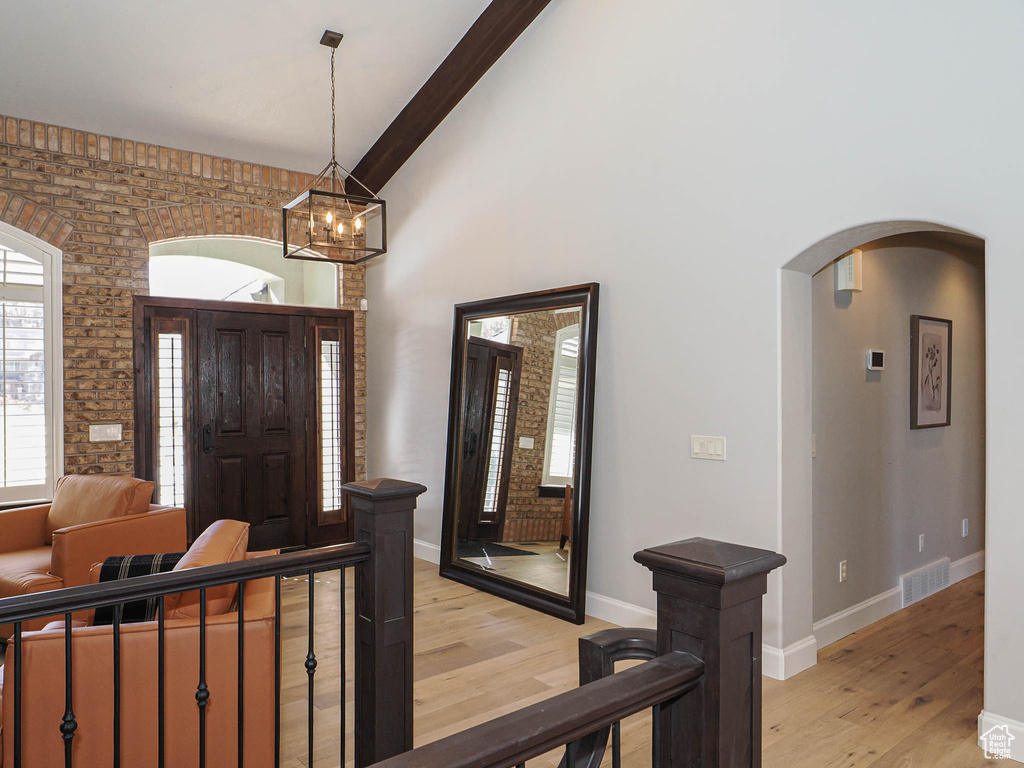 Entrance foyer with high vaulted ceiling, arched walkways, visible vents, and light wood finished floors