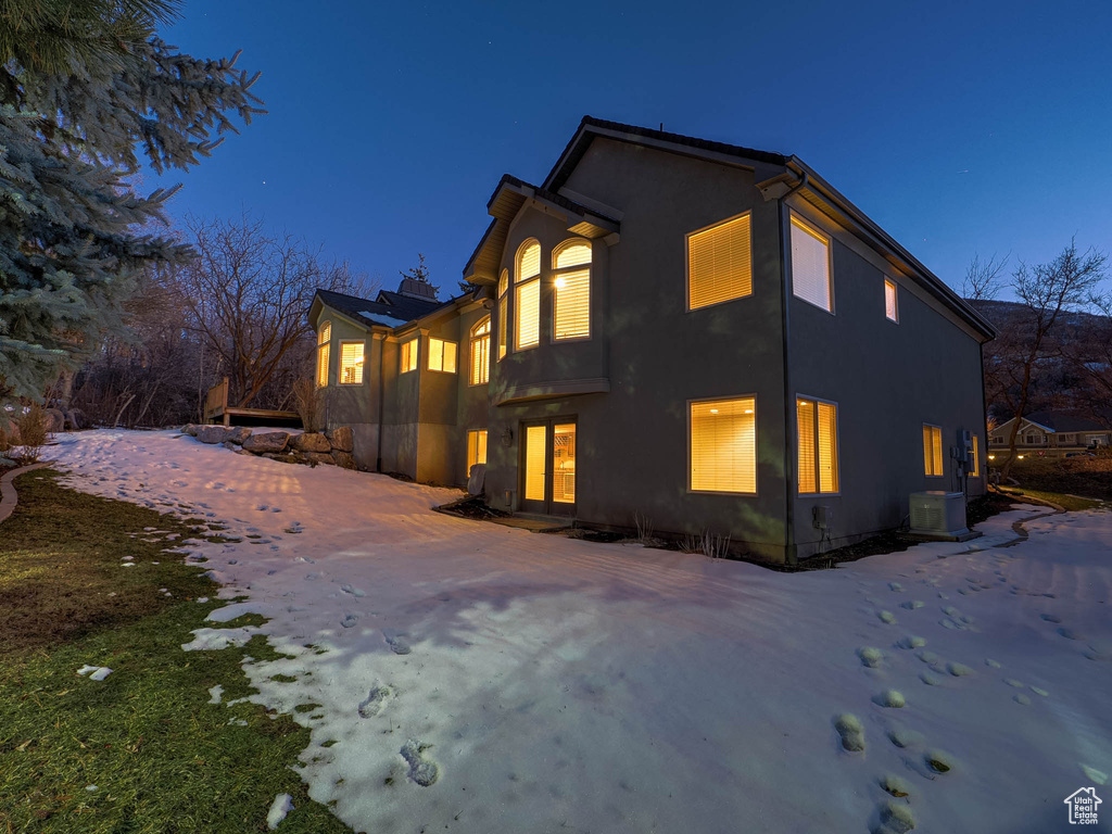 Snow covered house featuring driveway and stucco siding