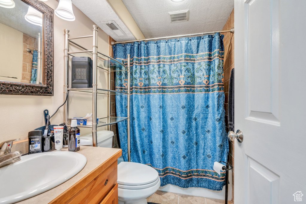 Bathroom with a textured ceiling, visible vents, vanity, and toilet