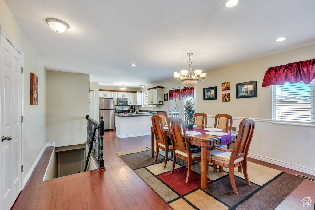 Dining area with recessed lighting, visible vents, baseboards, wood-type flooring, and an inviting chandelier
