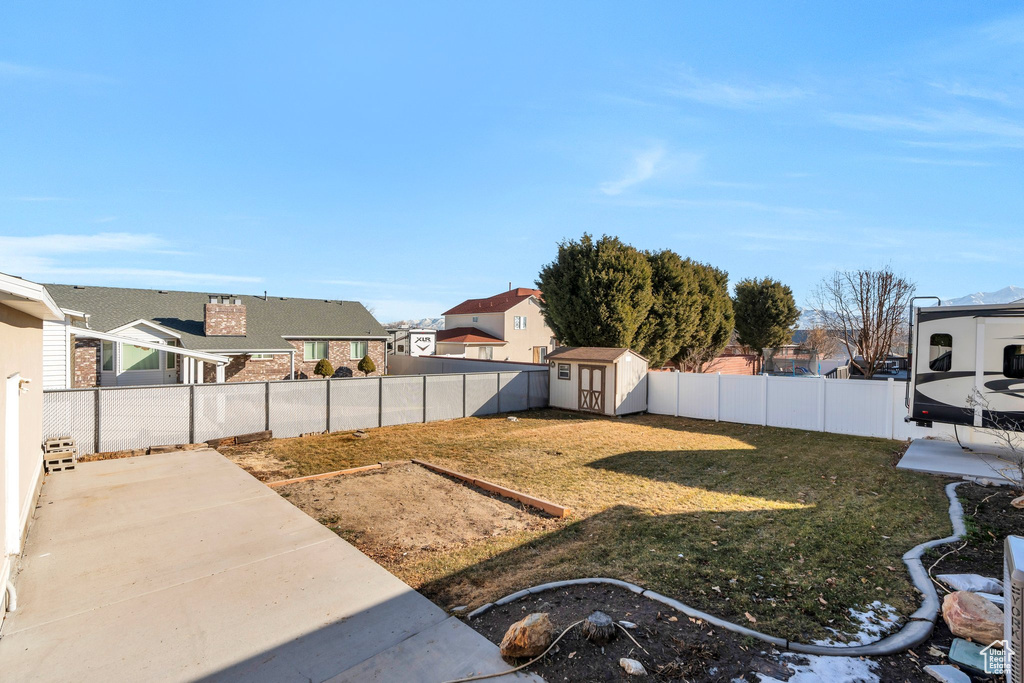 View of yard with an outbuilding, a residential view, a patio, and a storage shed