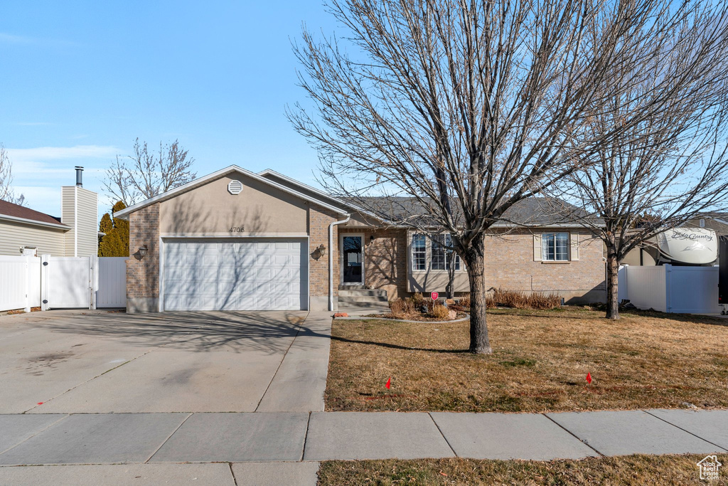 Ranch-style home with concrete driveway, an attached garage, fence, and a front yard