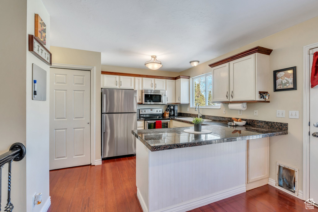 Kitchen with a peninsula, white cabinets, and stainless steel appliances