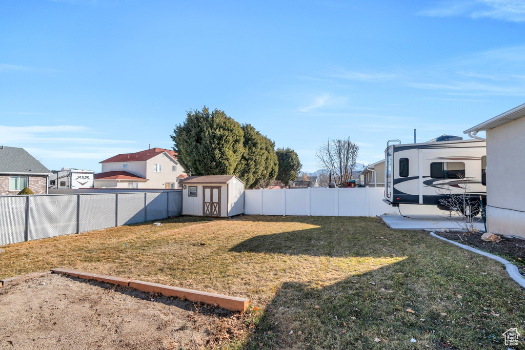 View of yard with a storage shed, an outbuilding, a fenced backyard, and a residential view
