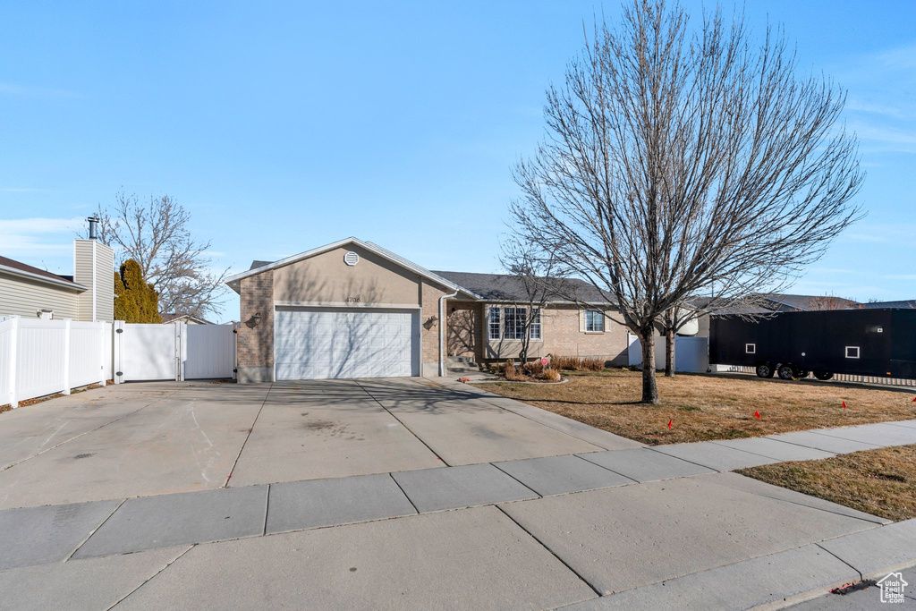 View of front facade featuring concrete driveway, an attached garage, fence, and stucco siding