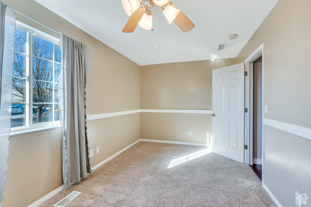 Unfurnished room featuring light carpet, baseboards, visible vents, and a ceiling fan