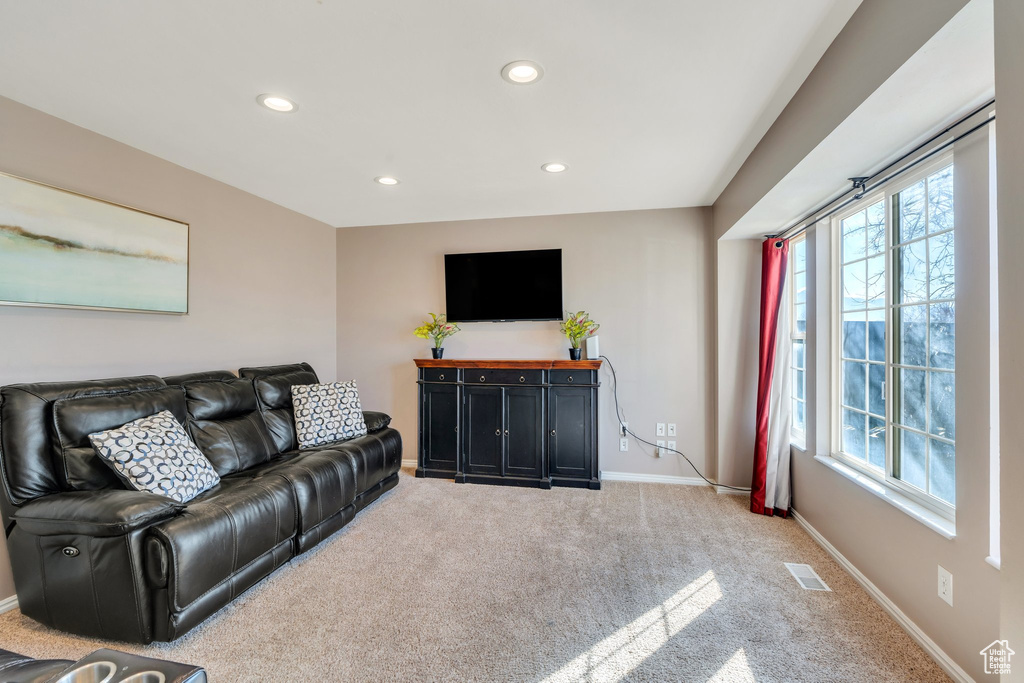 Living area featuring recessed lighting, visible vents, baseboards, and light colored carpet