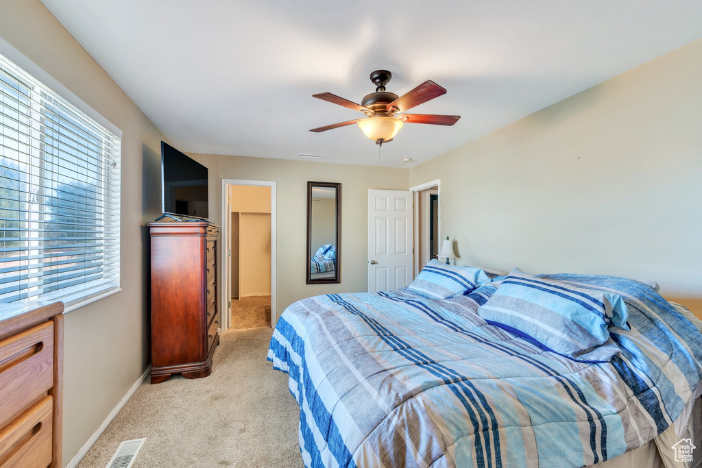 Bedroom with baseboards, a spacious closet, visible vents, and light colored carpet