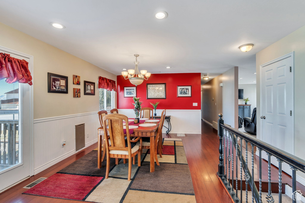 Dining room with a wainscoted wall, a notable chandelier, recessed lighting, visible vents, and dark wood-type flooring