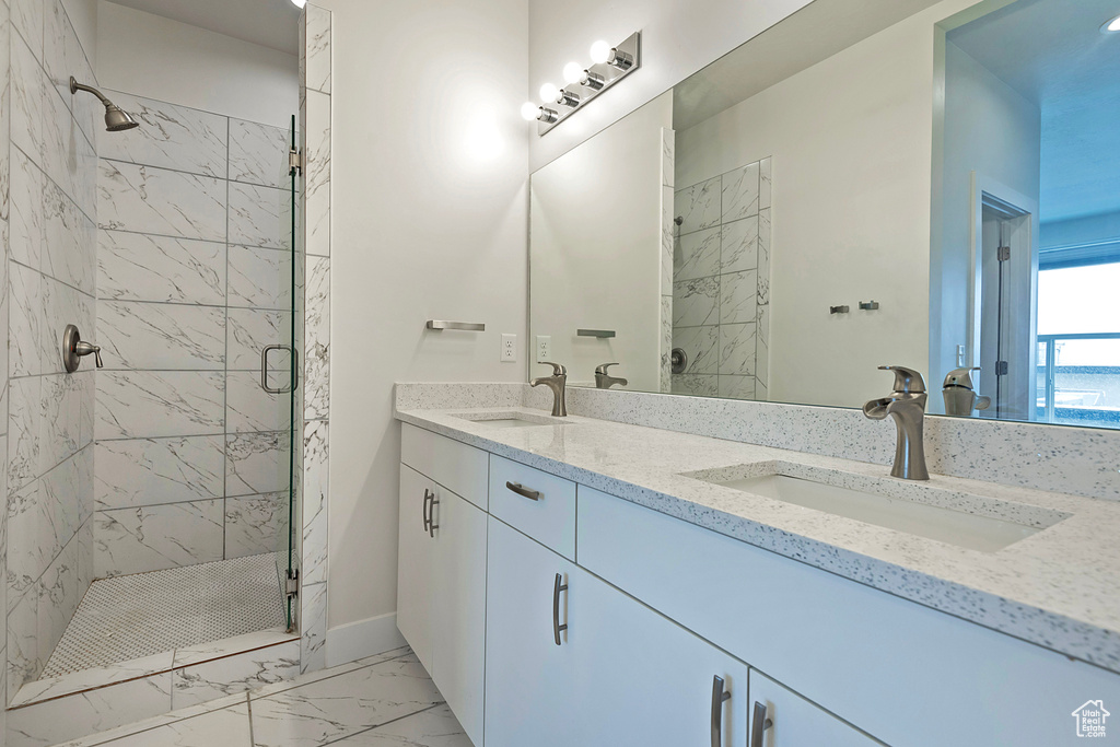 Bathroom featuring marble finish floor, a sink, a shower stall, and double vanity