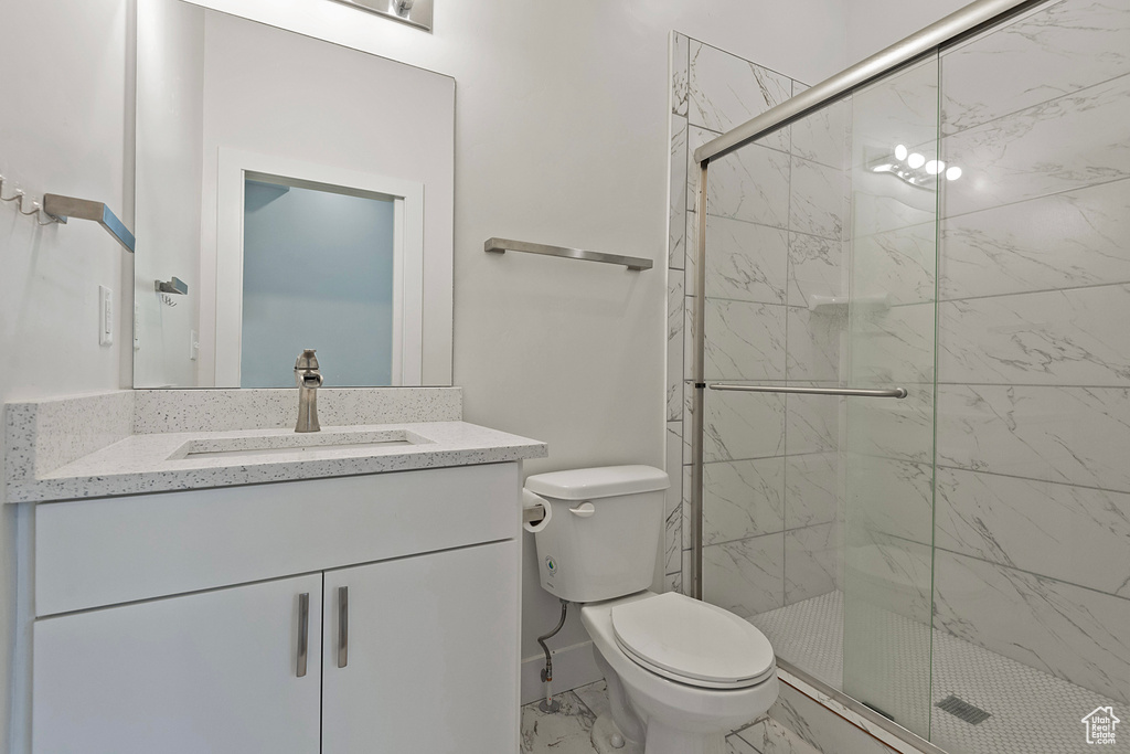 Bathroom with toilet, marble finish floor, a shower stall, and vanity