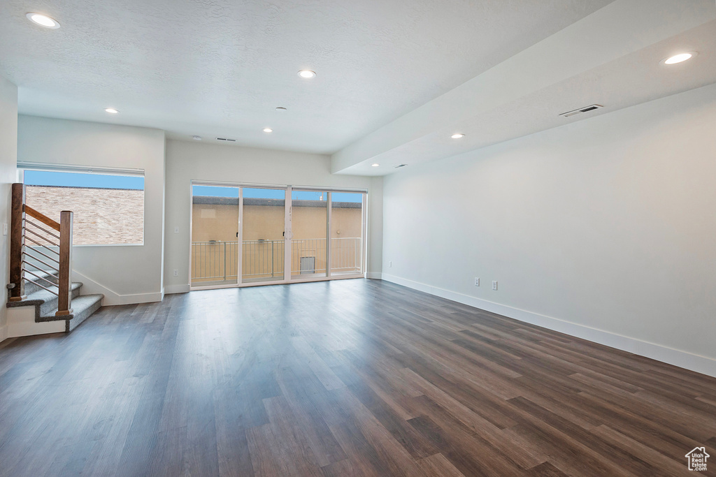 Unfurnished living room with visible vents, a textured ceiling, baseboards, and dark wood-type flooring