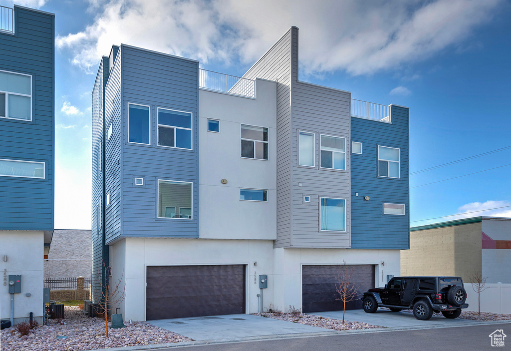 View of front of house with driveway, stucco siding, and central air condition unit