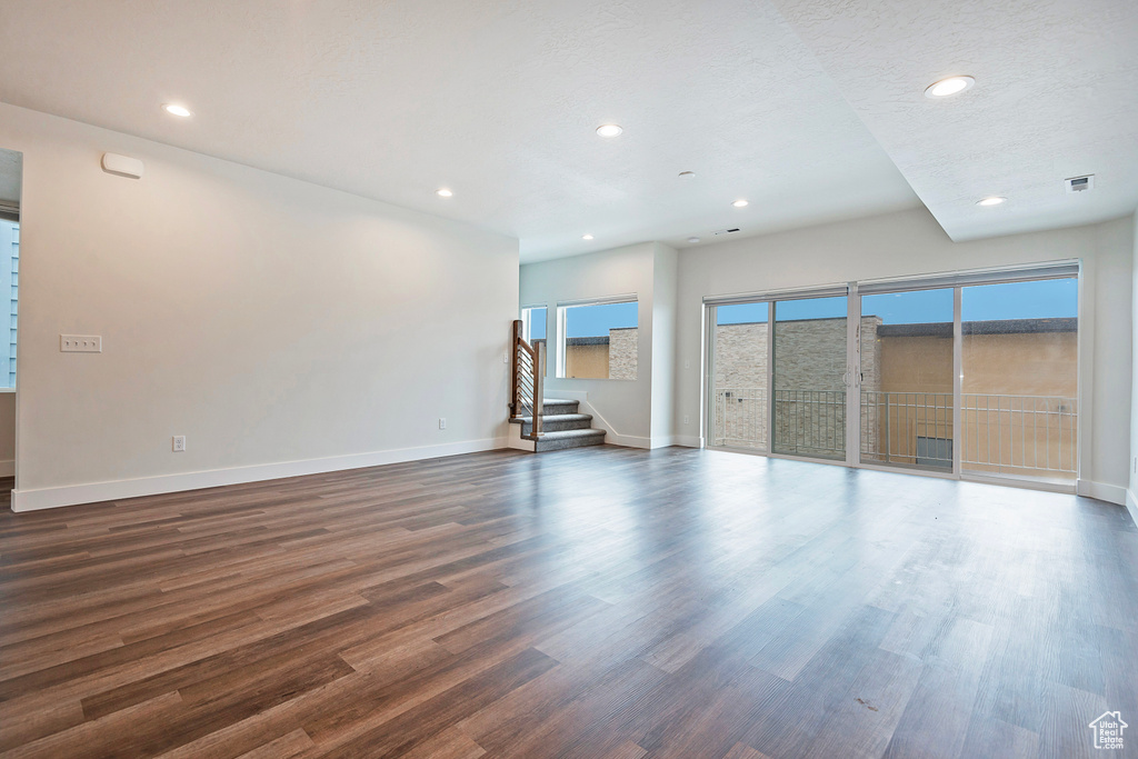 Unfurnished living room with stairs, dark wood-type flooring, recessed lighting, and baseboards