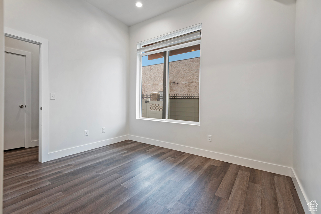 Spare room featuring baseboards, dark wood-style flooring, and recessed lighting