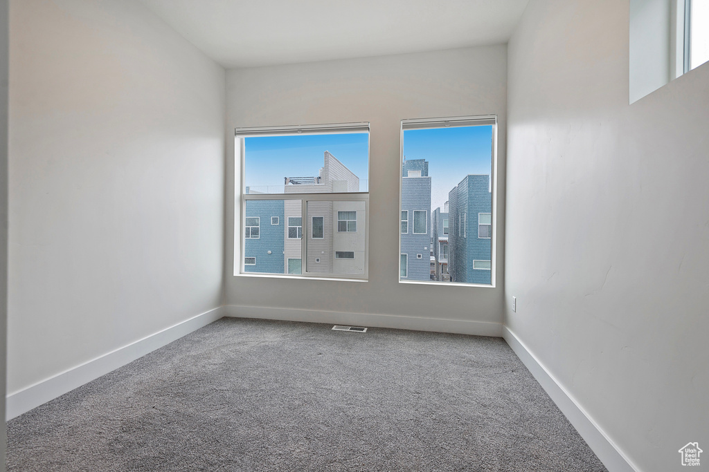 Carpeted spare room with baseboards, visible vents, and a city view