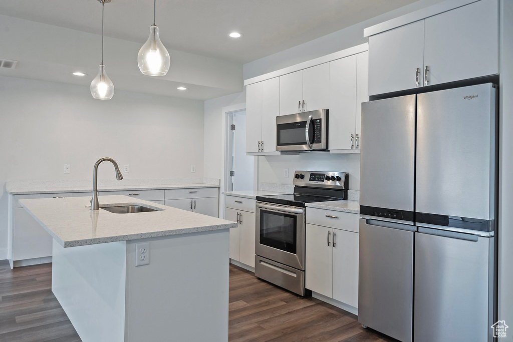 Kitchen featuring a center island with sink, light countertops, appliances with stainless steel finishes, white cabinetry, and a sink