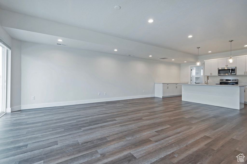 Unfurnished living room featuring baseboards, wood finished floors, visible vents, and recessed lighting