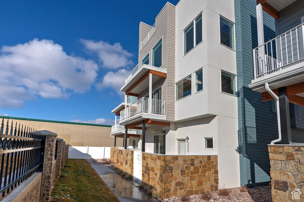 View of property exterior featuring stone siding, fence, and stucco siding