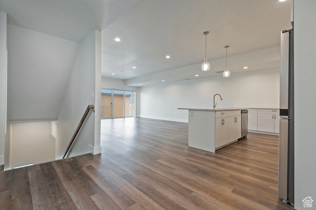 Kitchen with an island with sink, dark wood-style floors, open floor plan, light countertops, and white cabinetry