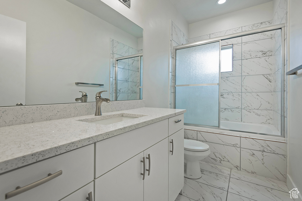 Full bath featuring toilet, marble finish floor, tiled shower / bath, and vanity