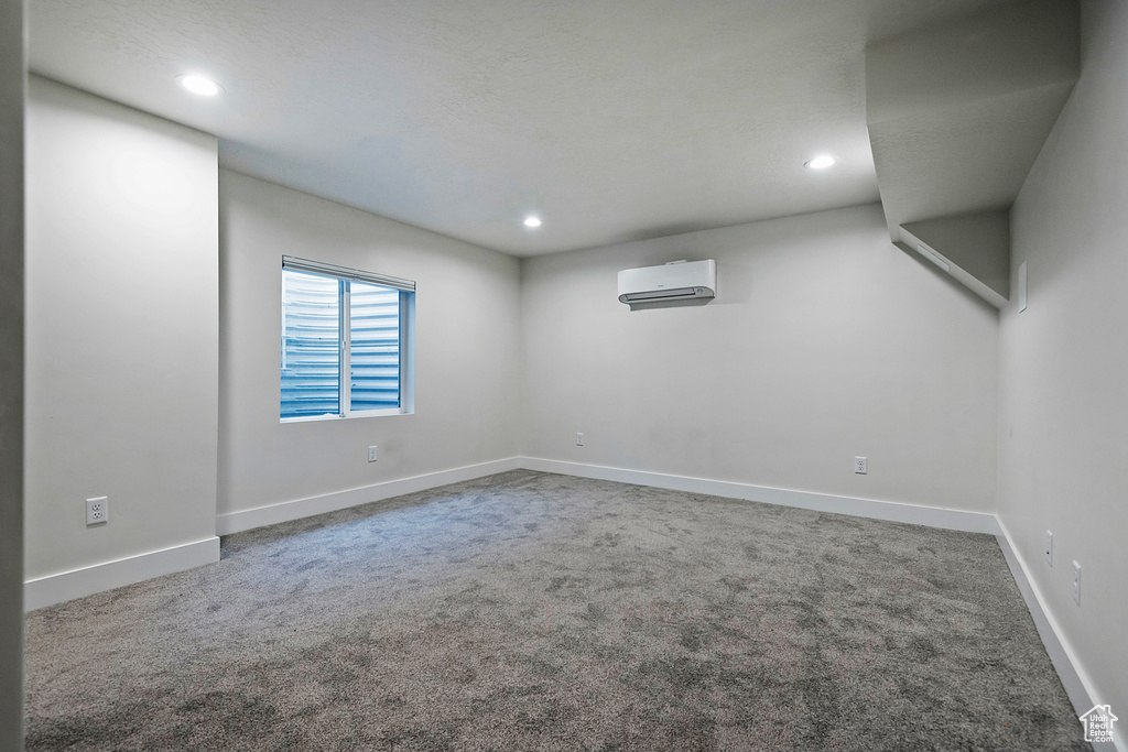 Spare room with a wall unit AC, baseboards, carpet flooring, and recessed lighting