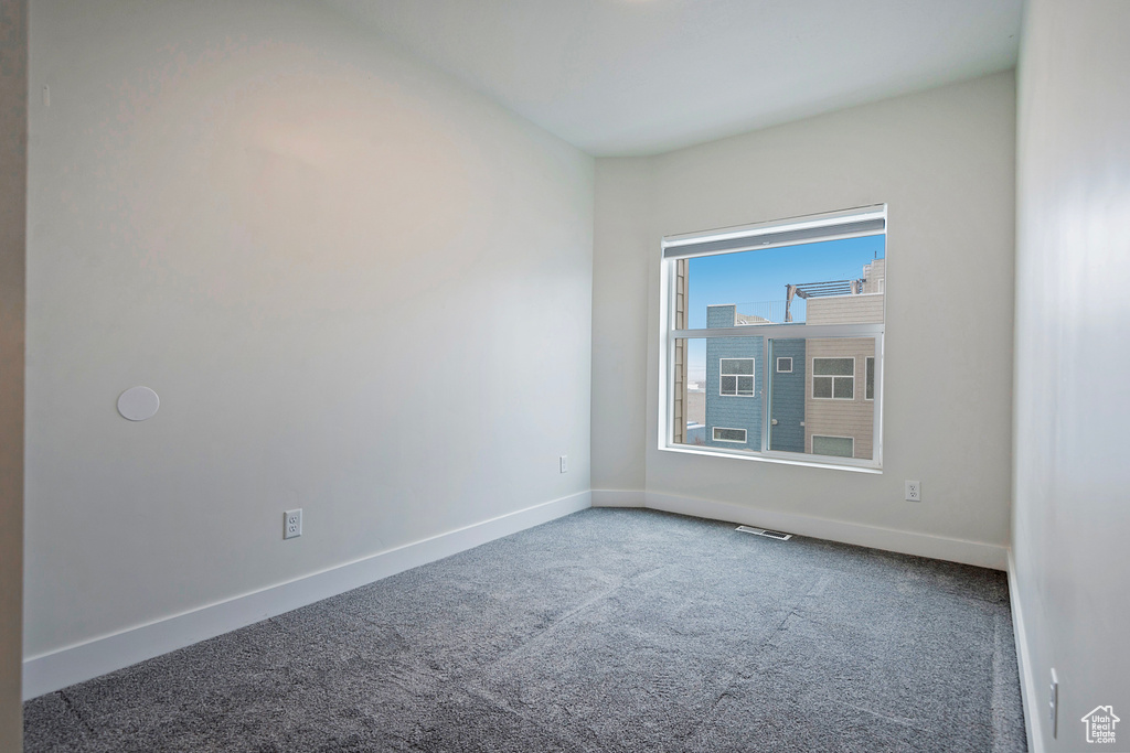 Carpeted empty room featuring visible vents and baseboards