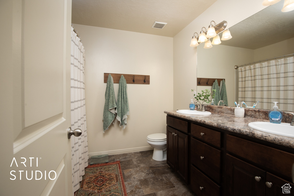 Bathroom with visible vents, a sink, baseboards, and double vanity