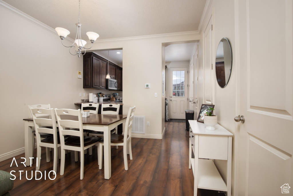 Dining area with ornamental molding, dark wood-style flooring, a notable chandelier, and baseboards