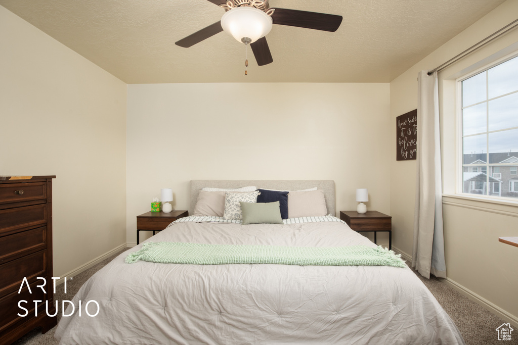 Carpeted bedroom featuring ceiling fan, a textured ceiling, and baseboards