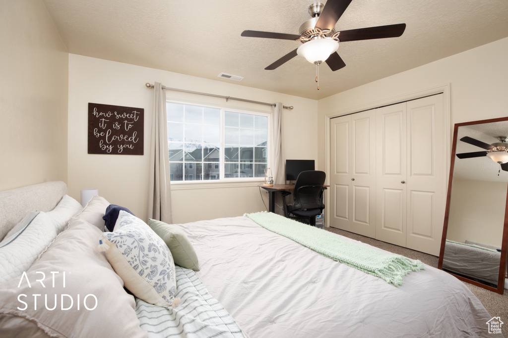 Bedroom with visible vents, ceiling fan, carpet, a textured ceiling, and a closet