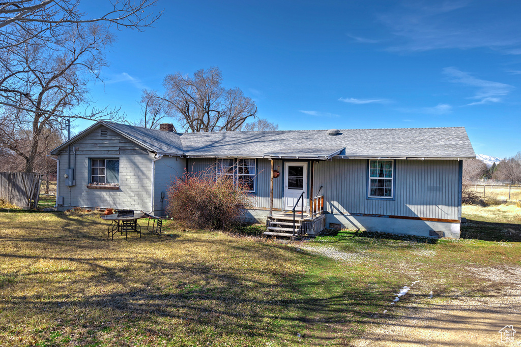 Back of house featuring crawl space, roof with shingles, a lawn, and a chimney