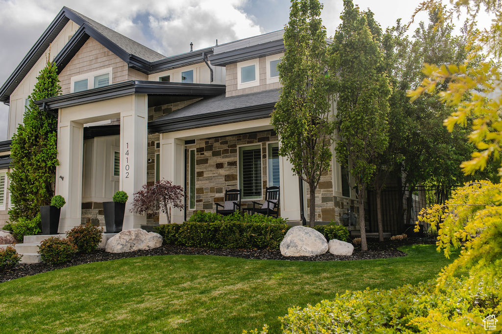 View of front of property featuring stone siding, a front yard, and covered porch