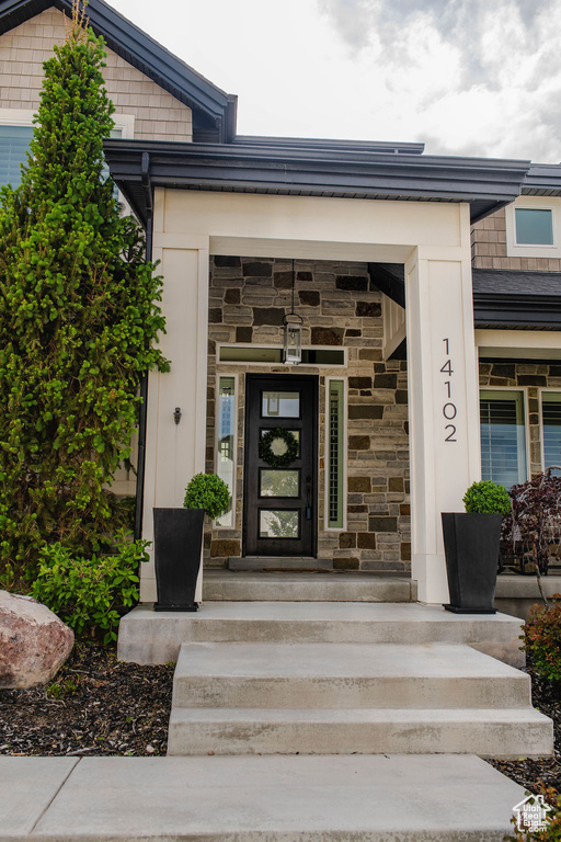 Doorway to property with stone siding and covered porch