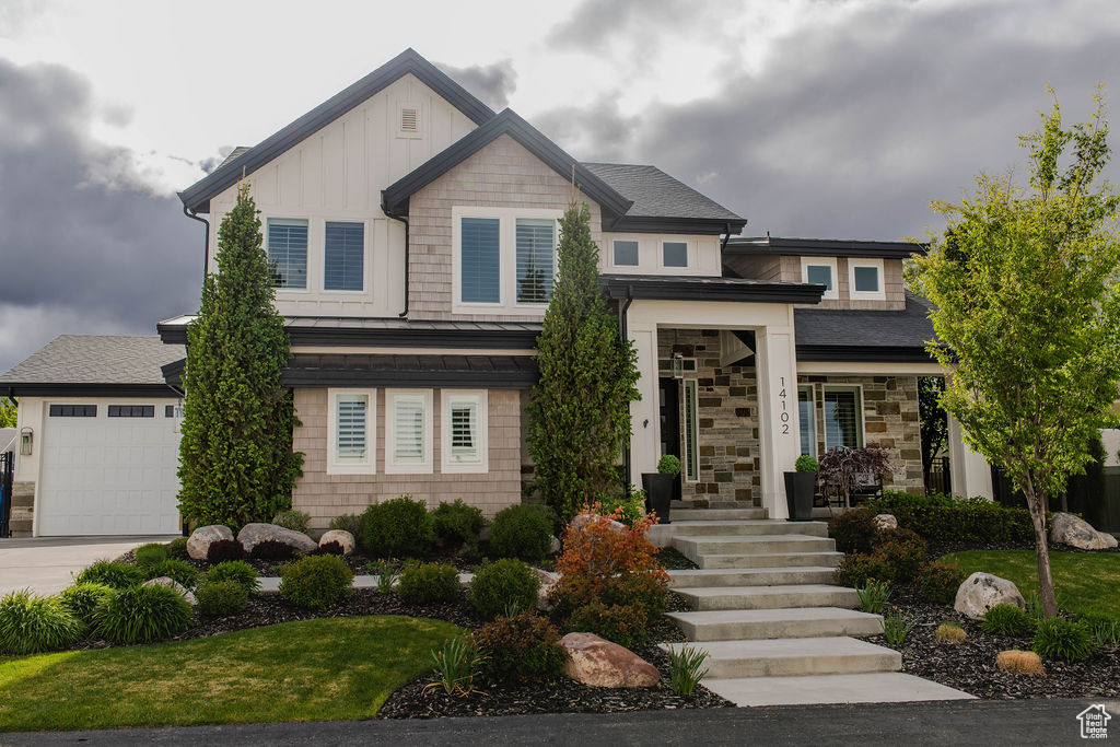 View of front of house featuring a standing seam roof, driveway, metal roof, board and batten siding, and an attached garage