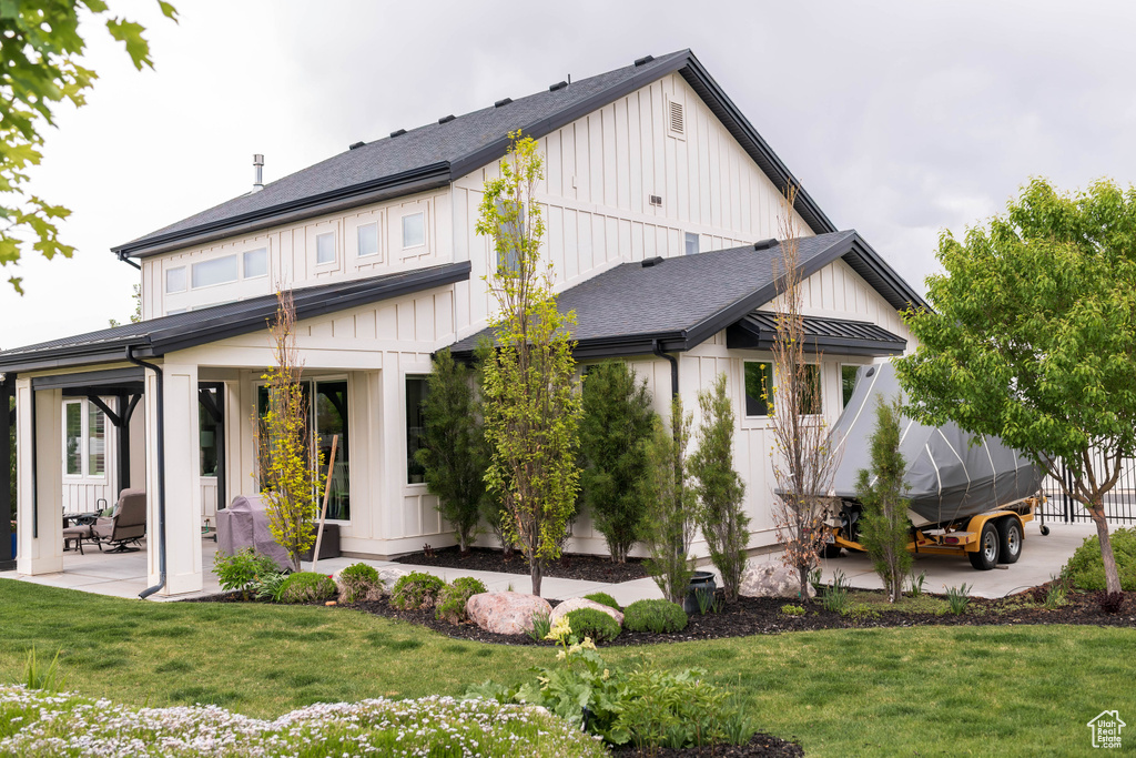 Back of house featuring board and batten siding, a patio area, and a yard
