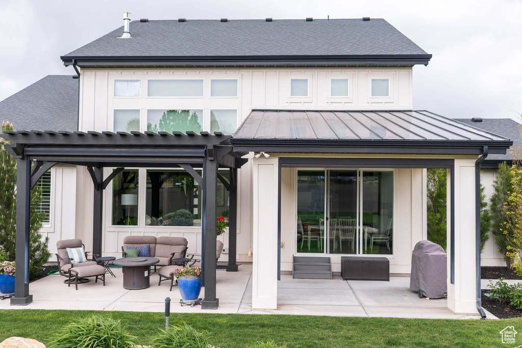 Back of house featuring an outdoor living space with a fire pit, a patio, a standing seam roof, board and batten siding, and a pergola